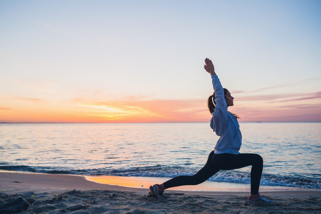 young woman doing sport exercises on sunrise beach in morning, stretching, healthy lifestyle, yoga