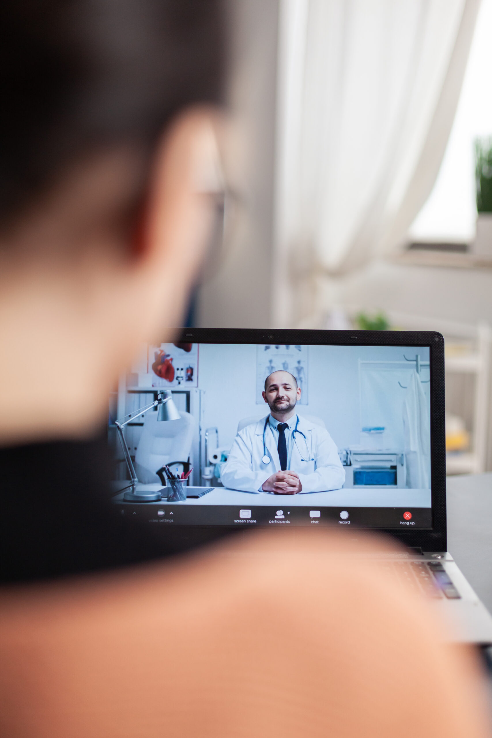 student working from home videocalling doctor on laptop.